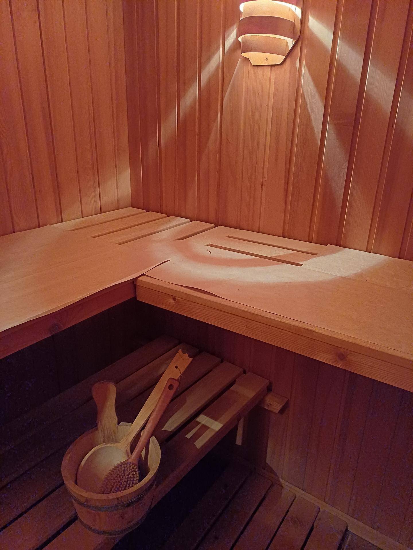 Holzverkleidete Sauna mit Bänken und traditionellem Eimer und Kelle.