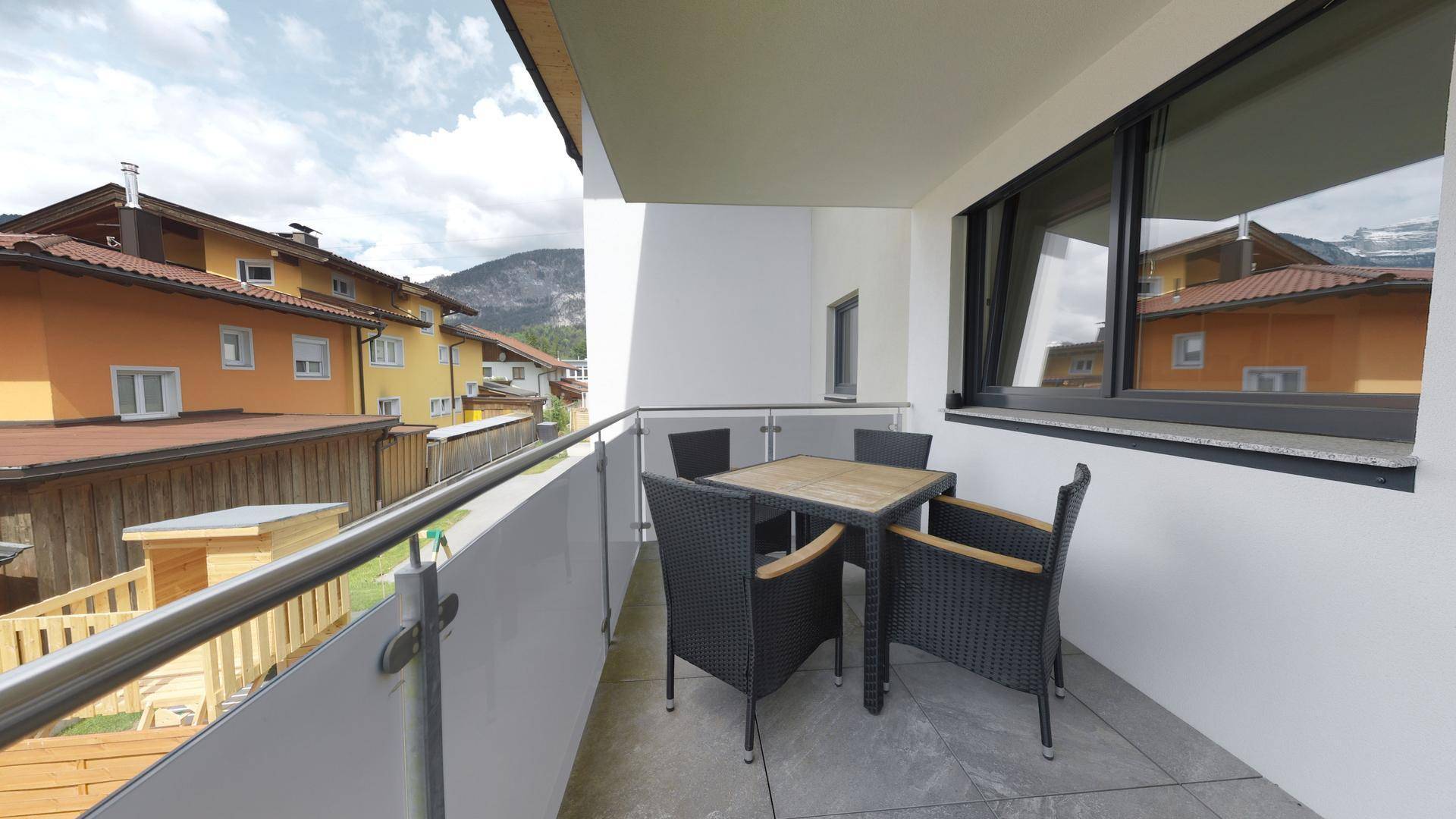 Möblierter Balkon mit Blick auf die umliegenden Häuser und Berge.