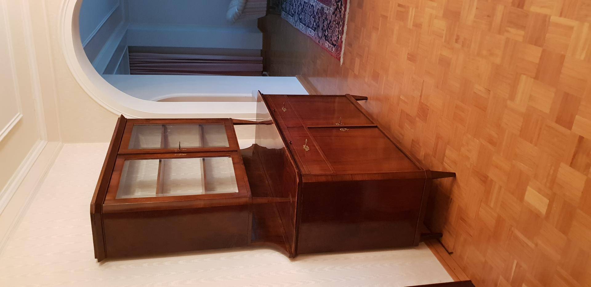 Antiker Holzschrank in einem Flur mit Parkettboden und einem eleganten Rundbogen.