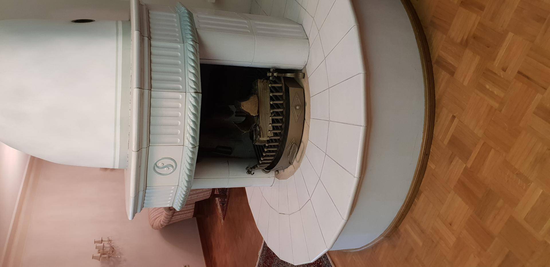 Detailansicht eines traditionellen weißen Kachelofens mit Fliesenbasis im Wohnbereich.