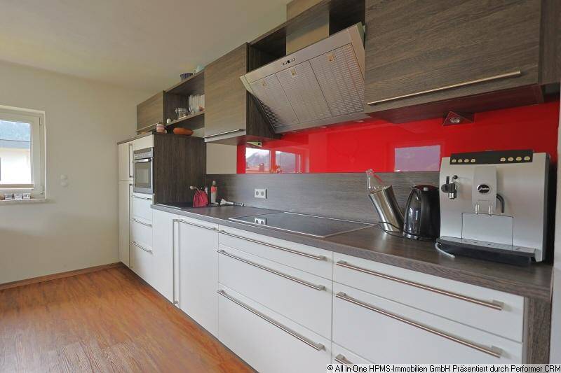 Moderne Küche mit roten Akzenten, Induktionskochfeld und hochwertigen Einbaugeräten.