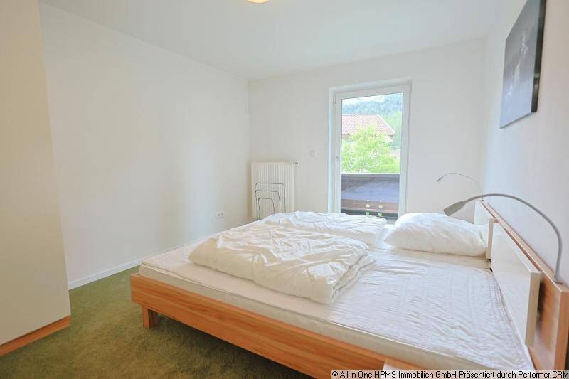 Schlafzimmer mit Doppelbett, grünem Teppichboden und Zugang zu einem Balkon.