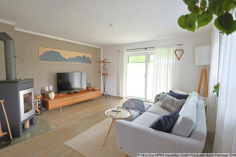 Helles Wohnzimmer mit Kaminofen, Zugang zum Balkon und modernem Interieur.