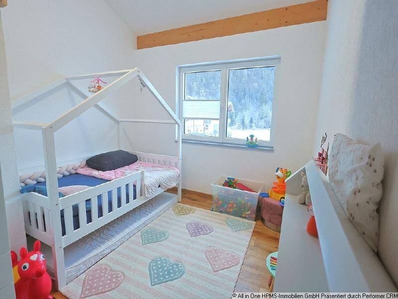 Kinderzimmer mit Holzboden, hellem Fenster und einem charmanten Hausbett für kleine Bewohner.