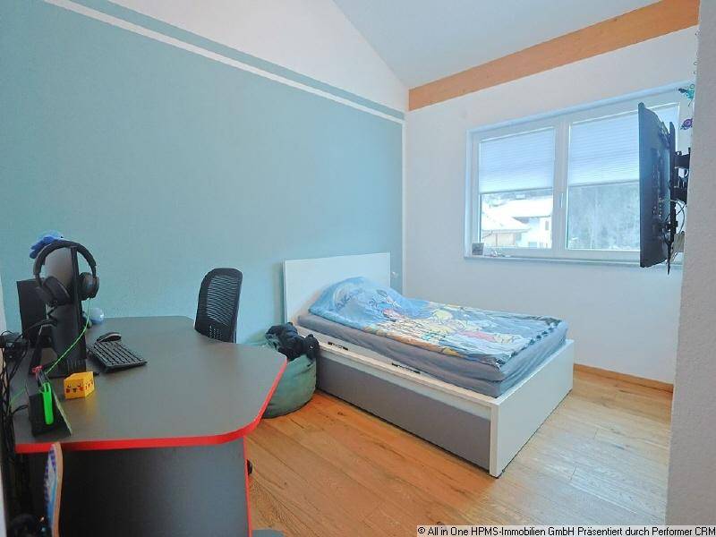 Jugendzimmer mit Holzboden, Schreibtisch und einem Bett, ideal für Kinder oder Gäste.