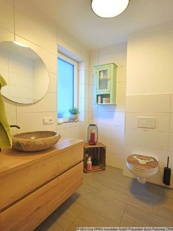 Modernes Badezimmer mit Natursteinwaschbecken, Holzunterschrank und Wand-WC.