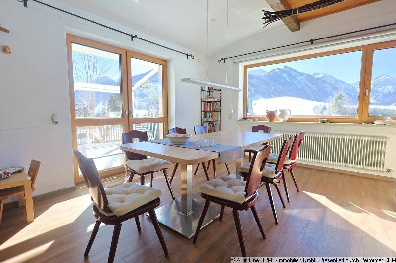 Geräumiger Essbereich mit Holztisch und Stühlen, großen Fenstern und Blick auf die Berge.