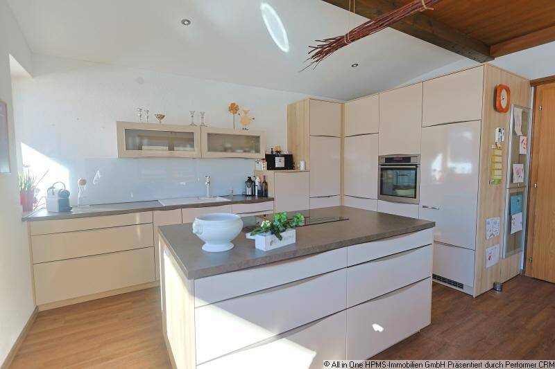 Moderne Küche mit heller Kücheninsel, integrierten Geräten und Holzbalken an der Decke.