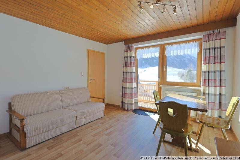 Gemütlicher Wohn-Essbereich mit Sofa, Esstisch und Balkonzugang mit Bergblick.