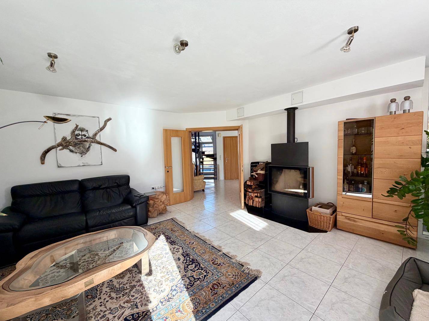 Gemütliches Wohnzimmer mit Kaminofen, Fliesenboden und Holzelementen.