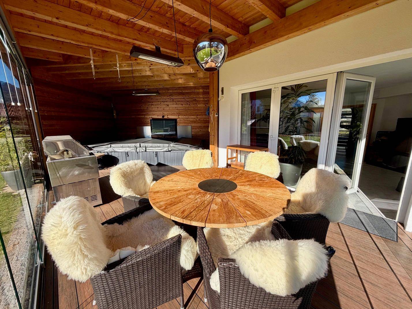 Überdachte Terrasse mit Holzboden, Esstisch und Whirlpool für entspannte Stunden.