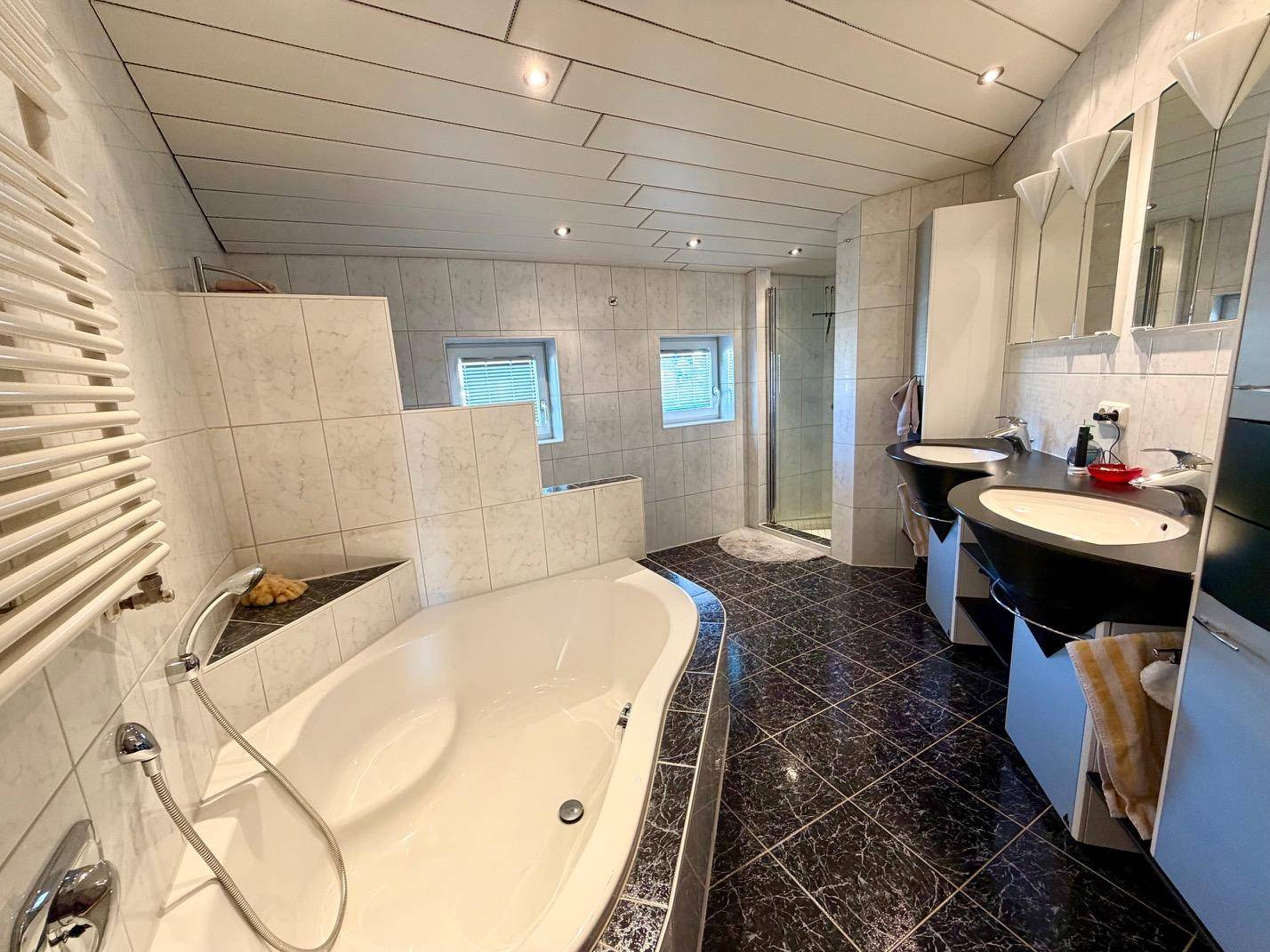 Großes Badezimmer mit Doppelwaschbecken, Badewanne und separater Dusche.