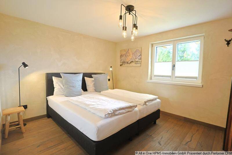 Komfortables Schlafzimmer mit Doppelbett, Holzboden und Fenster mit Blick ins Grüne.