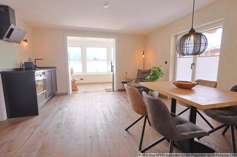 Moderner Essbereich mit Holztisch und Blick in ein angrenzendes, helles Wohnzimmer.