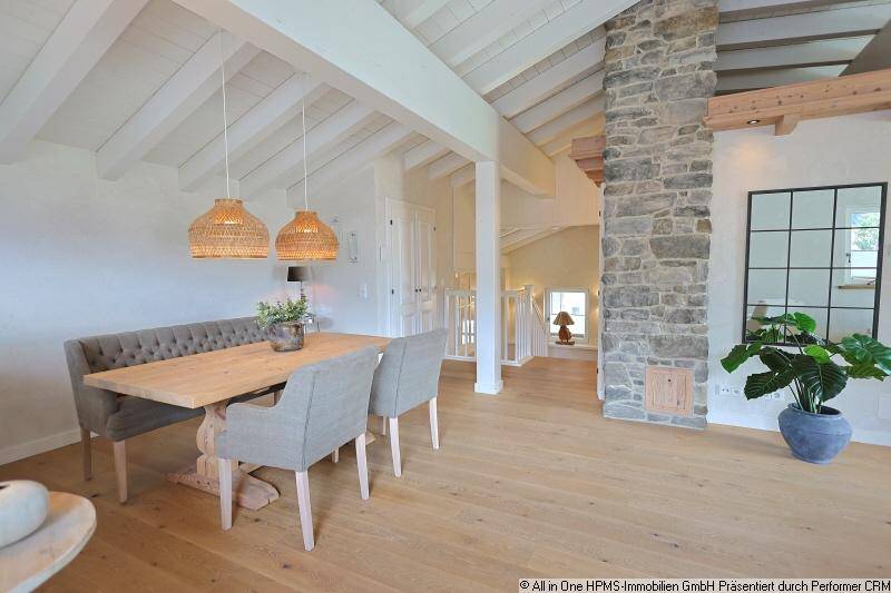 Offener Essbereich mit Holztisch, Steinwand und Blick auf die Treppe zum oberen Stockwerk.
