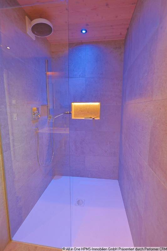Elegante begehbare Dusche mit Glaswand, Regendusche und indirekter Beleuchtung.