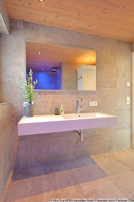Modernes Badezimmer mit schwebendem Waschbecken, großem Spiegel und Holzdecke.