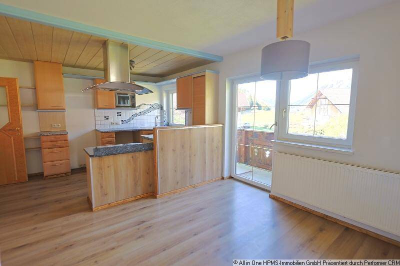 Offene Küche mit Holzelementen, Laminatboden und Zugang zu einem kleinen Balkon.