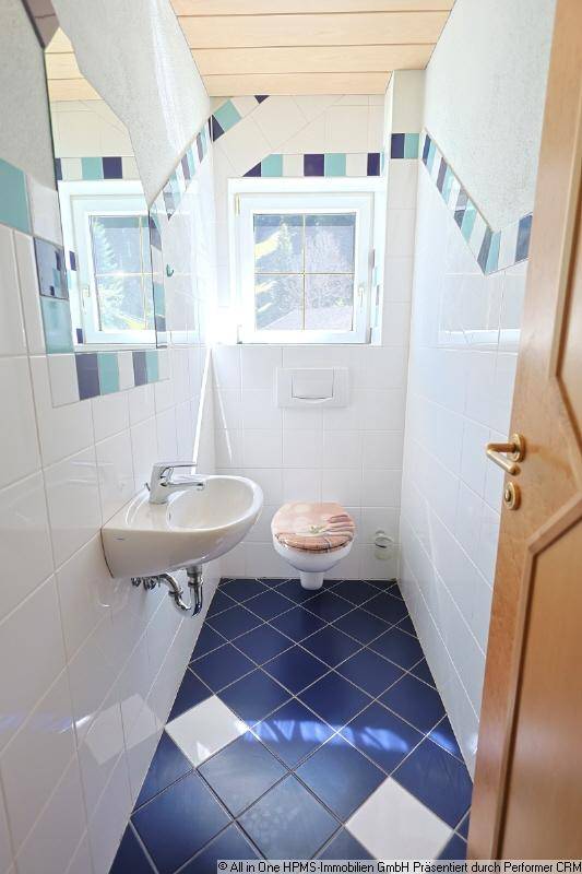 Kleines Gäste-WC mit blauen Fliesen, Waschbecken und Fenster für Tageslicht.