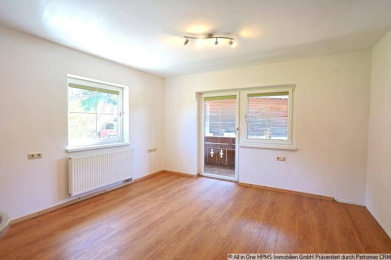 Helles Zimmer mit Laminatboden, weißen Wänden und Zugang zu einem Balkon.