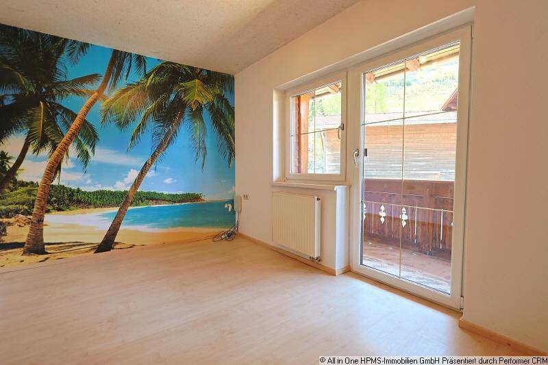 Schlafzimmer mit auffälliger tropischer Tapete, Laminatboden und Balkonzugang.