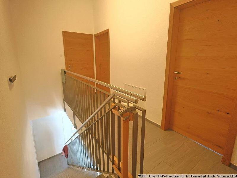 Heller Flur mit Treppenaufgang, modernen Holztüren und Fliesenboden in schlichtem Design.
