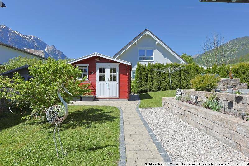 Gepflegter Gartenbereich mit Gartenhaus, Steinweg und Blick auf die umliegenden Berge.