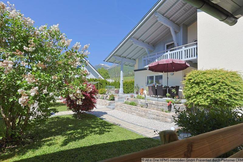 Weitläufiger Garten mit blühenden Sträuchern und Blick auf das Haus mit Balkon und Terrasse.