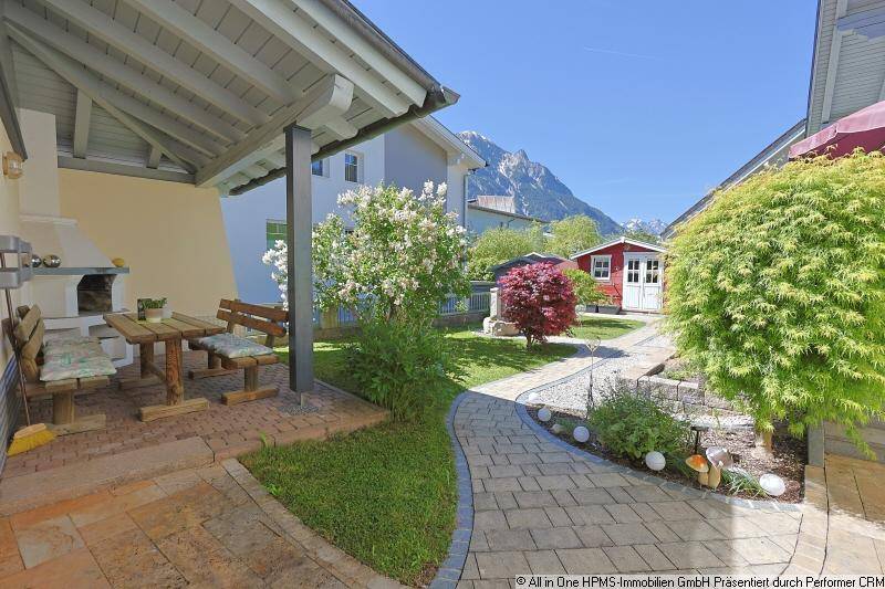 Gemütlicher Gartenbereich mit Grillplatz und rustikaler Sitzgruppe, umgeben von viel Grün.