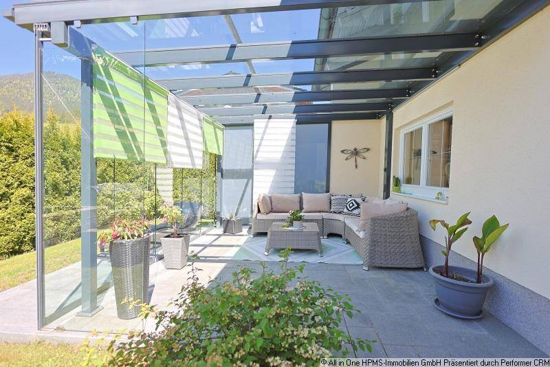 Überdachte Terrasse mit bequemen Loungemöbeln und Glasdach, ideal für entspannte Stunden im Freien.