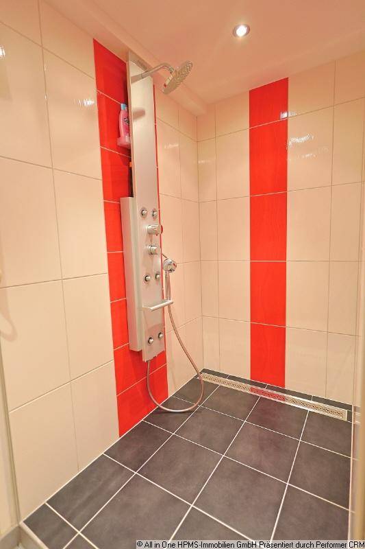 Moderne Duschkabine mit roten Akzentfliesen und Regendusche.