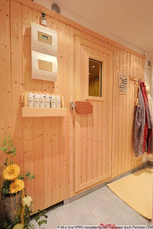 Holzvertäfelte Sauna mit Steuerungselementen und Zubehör, bereit zur Nutzung.
