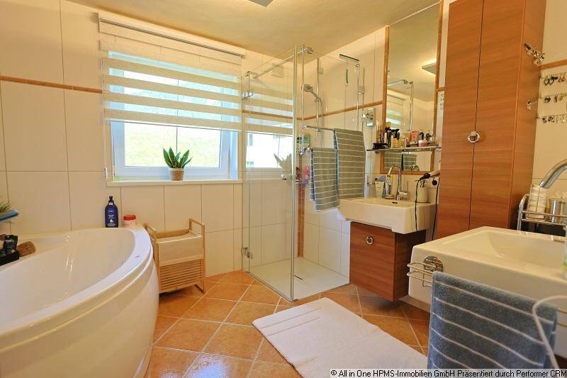 Helles Badezimmer mit Badewanne, Dusche, Doppelwaschbecken und Fenster.