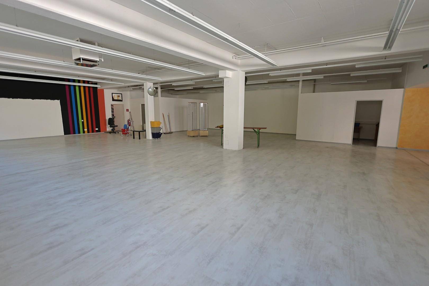 Weitläufiger Gewerberaum mit Betonboden, Säulen und einer farbenfrohen Wandgestaltung.