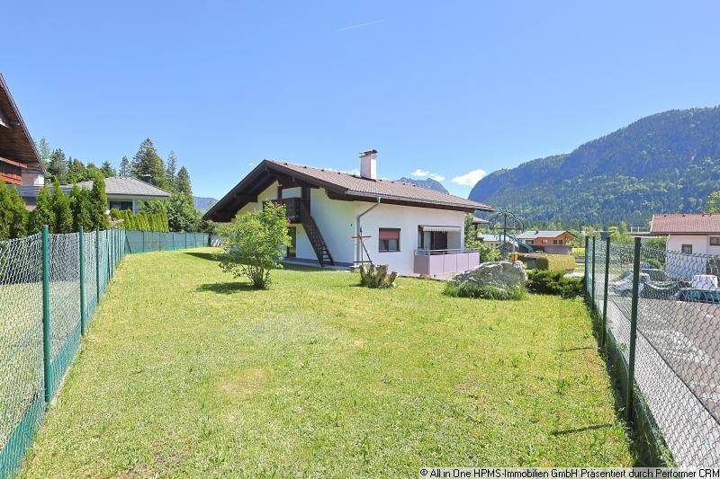 Großer Rasenbereich neben dem Haus mit Blick auf die umliegende Berglandschaft.