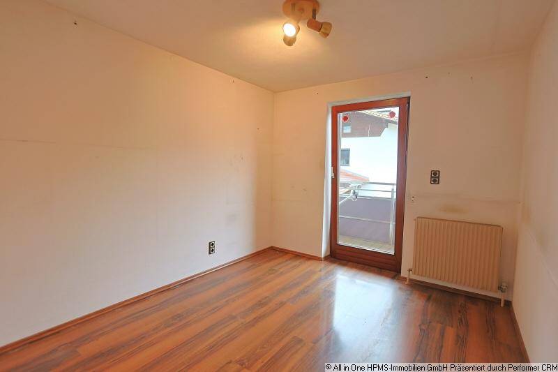 Zimmer mit dunklem Holzboden, weißen Wänden und direktem Zugang zu einem Balkon.