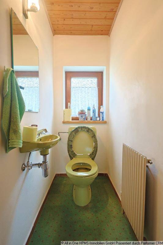 Separate Toilette mit grünem WC, passendem Waschbecken und einem Fenster.