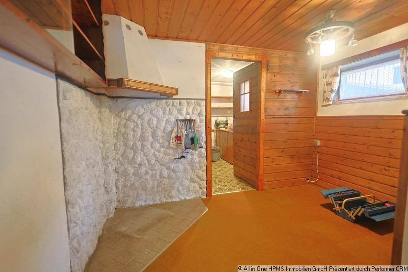 Rustikaler Hauswirtschaftsraum mit Holzverkleidung, Steinwand und einem traditionellen Ofenbereich.