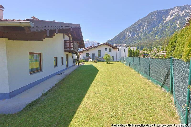 Seitenansicht des Hauses mit langem Rasenstreifen und beeindruckendem Bergblick im Hintergrund.