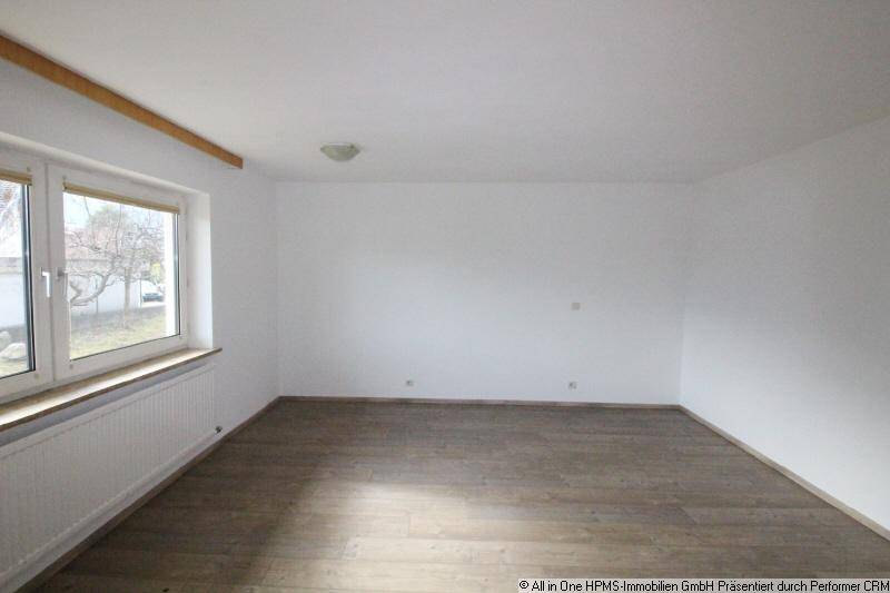 Heller, leerer Raum mit Laminatboden und großem Fenster.