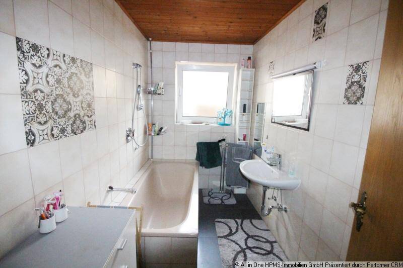 Badezimmer mit Badewanne, Dusche, Einzelwaschbecken und gemusterten Fliesen.