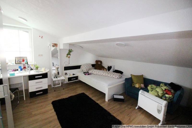Schlafzimmer im Dachgeschoss mit schräger Decke, Bett, Schreibtisch und Fenster.
