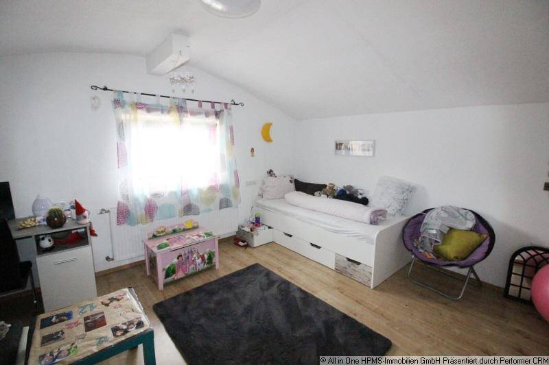 Kinderzimmer im Dachgeschoss mit schräger Decke, Bett und farbenfroher Dekoration.