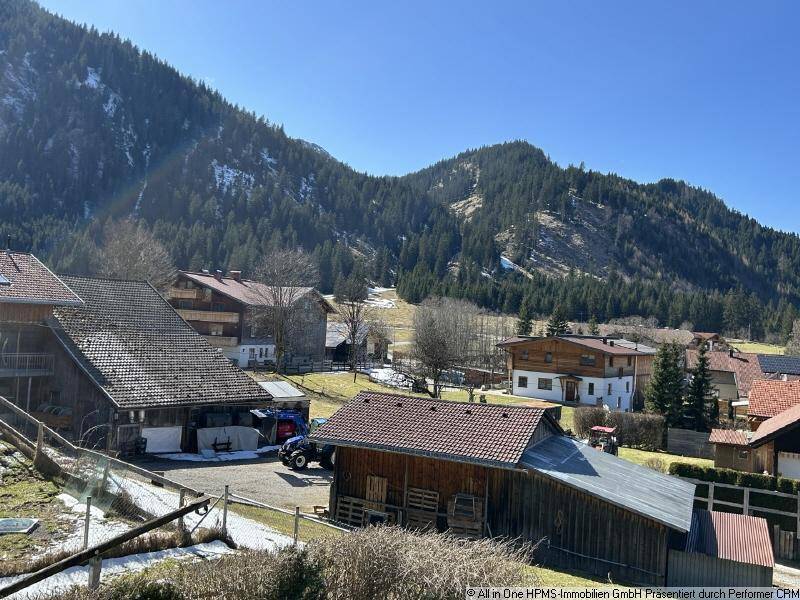 Malerischer Blick auf ein Bergdorf mit traditionellen Häusern und schneebedeckten Gipfeln.