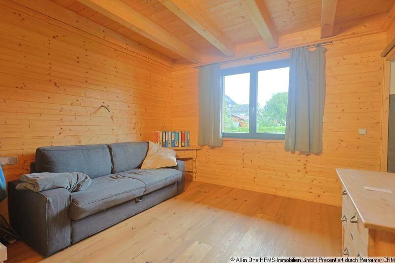 Freundliches Zimmer mit Holzwänden, Holzboden und einem bequemen Sofa, ideal als Gästezimmer.
