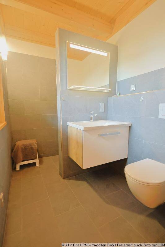 Modernes Badezimmer mit Waschtisch, WC und begehbarer Dusche, alles in neutralen Grautönen.