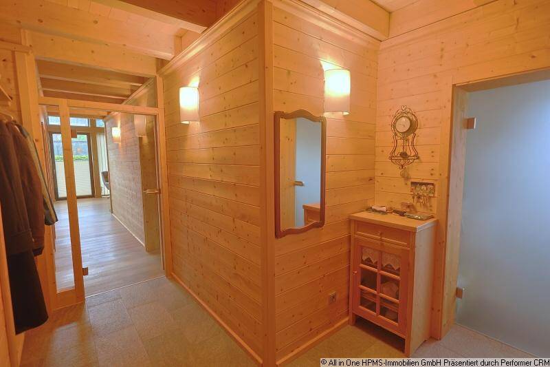 Heller Eingangsbereich mit Holzwänden, Garderobe und Blick in den offenen Wohnbereich.