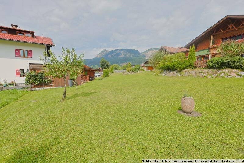 Große, gepflegte Rasenfläche des Gartens mit Blick auf die umliegenden Berge und traditionelle Häuser.