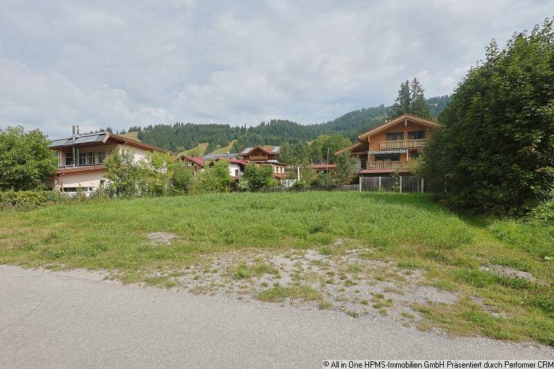 Blick vom Grundstück auf umliegende Wohnhäuser und die malerische Berglandschaft im Hintergrund.