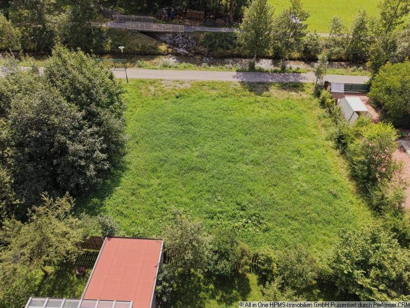 Luftaufnahme eines unbebauten Grundstücks mit Blick auf eine Brücke und bewaldete Hügel in der Ferne.
